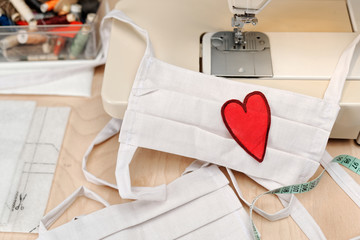 Homemade facemask against virus infection in detail with sewing machine and heart emblem