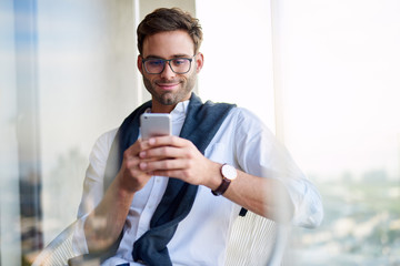 Stylish young man sitting at home using a cellphone