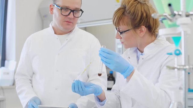 Chemist working with hemp CBD oil and tablet in laboratory