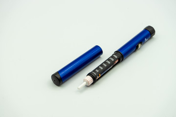 An insulin injection pen used by diabetics with insulin inside next to its lid isolated on a white background