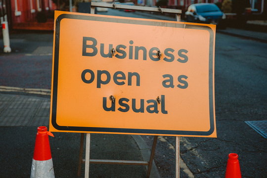 Business open as usual. Yellow sign stating business open as usual during lockdown and road works. Business open as usual sign on road. Business open as usual sign during coronavirus covid-19 pandemic