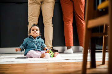 Adorable Afro American baby sitting on the floor at home