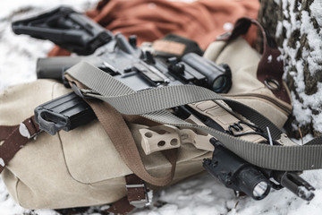 An assault rifle lies on a military briefcase in winter time.