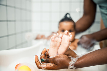 Afro American man holding tiny feet of newborn baby