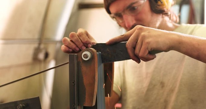 Bladesmith deburring a blade on belt grinder