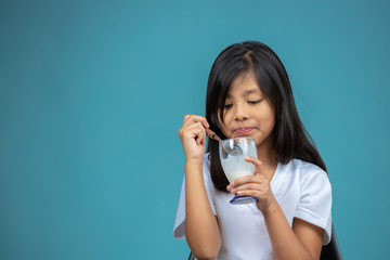 Fototapeta premium girl eating a glass of yogurt on blue background 