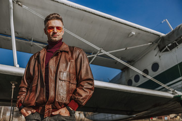 Young handsome man is standing near airplane