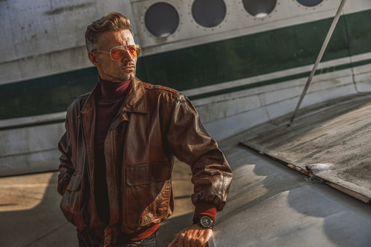 Stylish Man In Sunglasses Posing Near Airplane Wing