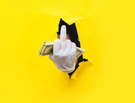 A hand in a white medical glove holds a bundle of hundred-dollar banknotes. The concept of a collapse of markets, the collapse of the exchange and the global crisis from the coronavirus. Fuck concept. - Powered by Adobe