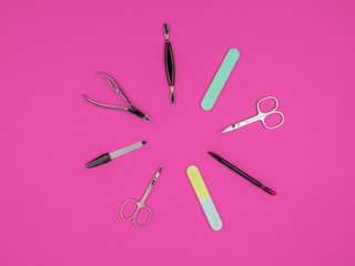 Fototapeta na wymiar Accessories for manicure, lying in a circle on a pink background.
