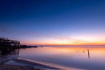 Naklejka premium purplish-orange sunset over the water, calm, night
