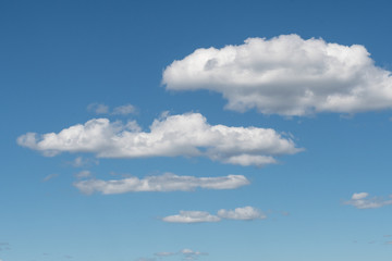 A group of white clouds almost symmetrical between the blue sky and some mountains in the south of...