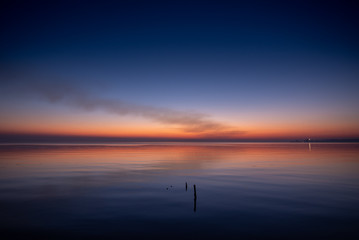 purplish-orange sunset over the water, calm, night