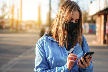 Coronavirus in Europe. the girl is standing by the road in a protective medical mask and talking on a cell phone.
