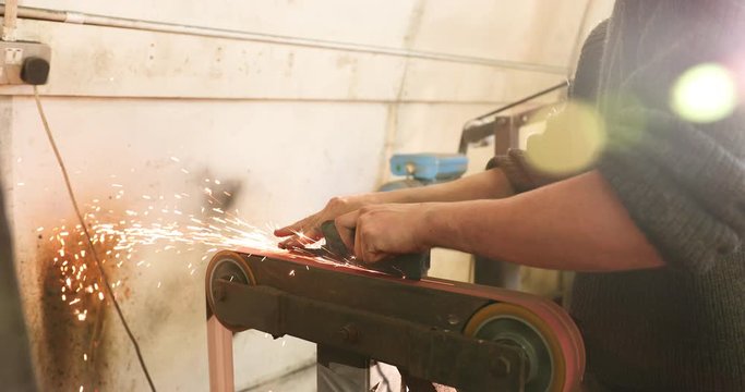 Bladesmith deburring a blade on belt grinder