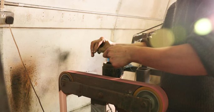 Bladesmith deburring a blade on belt grinder