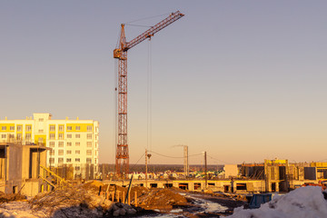 Fototapeta na wymiar on a spring evening, a tower crane builds buildings on the outskirts of the city
