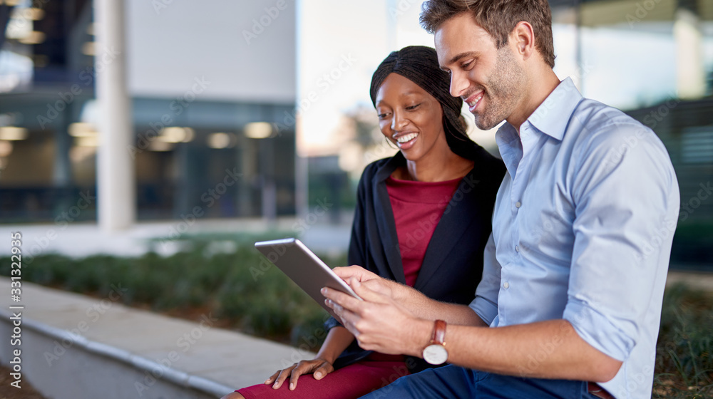 Wall mural diverse coworkers sitting outside working on a digital tablet