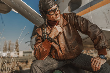 Attractive stylish pilot resting near airplane outdoors © Yakobchuk Olena