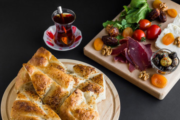 Traditional Ramadan,iftar begining meal with dry aged meat,tea,ramadan fresh   bread,walnut,apricot,cheese,olives and dry date fruits on the black surface.Conceptual image of Ramadan.