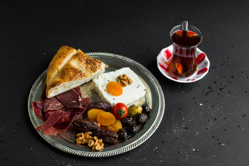 Traditional Ramadan,Iftar Menu with sliced ramadan bread,cheese,walnuts,dried date fruits,apricot,olives and dried age meat in the rustic metal plate with Turkish Tea.Ramadan Concept.