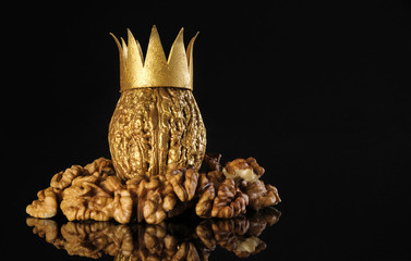 Golden walnut in a crown and walnut kernels on a black background. Walnut healthy food.