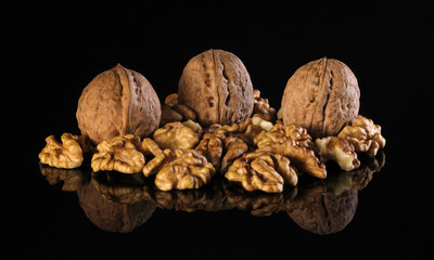Three walnuts and walnut kernels on a black table