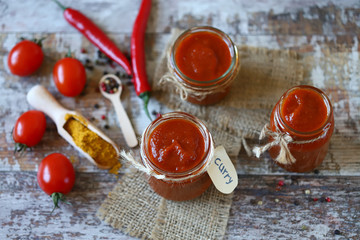 Fototapeta na wymiar Homemade Curry Sauce. Jars with curry sauce, tomatoes, seasonings.