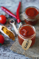 Homemade Curry Sauce. Jars with curry sauce, tomatoes, seasonings.