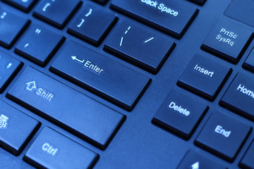 Keyboard classic black color Enter button in the cold light of the monitor