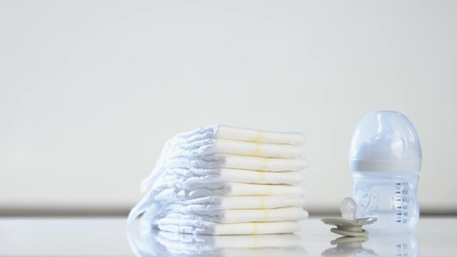 Baby diapers disappearing from the table. Close up shot with the bottle and pacifier. Timelapse.