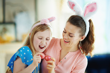 cheerful modern mother and child having egg tapping with eggs
