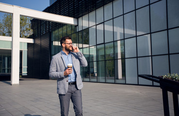 Man in suit holding cup of coffee and talking on the phone