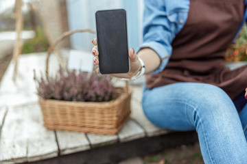Young woman demonstrating her cellular phone outdoors