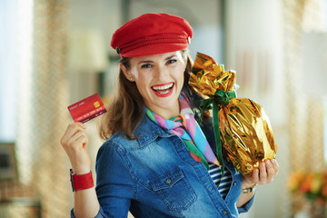 smiling woman showing credit card and holding easter egg