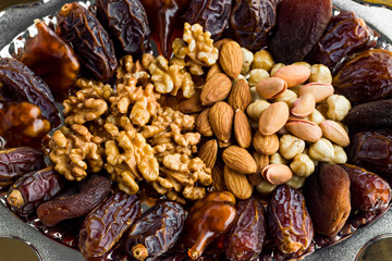 Luxury Dry Date Fruits,walnut,pistachio,hazelnuts and almonds in the stylish,golden tray,top view,close up.Conceptual image of Islamic Tradition Ramadan.