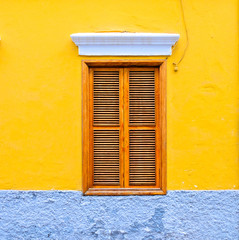 Yellow house, wooden shutters, closed windows.