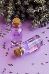 Essential Oil of Lavender in mini bottles on the pastel tone surface with dry lavender flower.