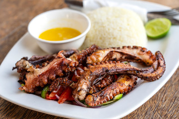 Fried octopus tentacles with white rice on a plate, close up