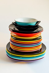 Colorful,clean dinner plates stacked on white surface.Close up taken,vertical image.