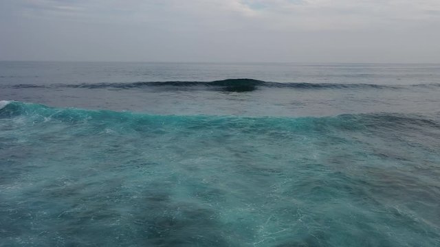 4K aerial view of a large beautiful Pacific wave from a height. Surfing on smooth rolling beautiful long waves. Sea blue, green charming water. Travel around the world. The bewitching beauty of nature