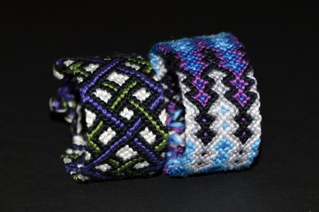 Colorful and multi-colored friendship bracelets handmade of embroidery bright floss and thread with knots isolated on black background