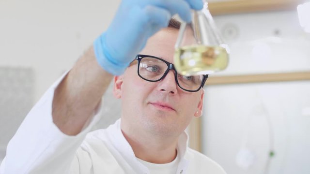 Close up of chemist working with hemp CBD oil and tablet in laboratory