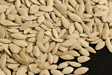 Pumpkin seeds on the black surface with copy space,top view