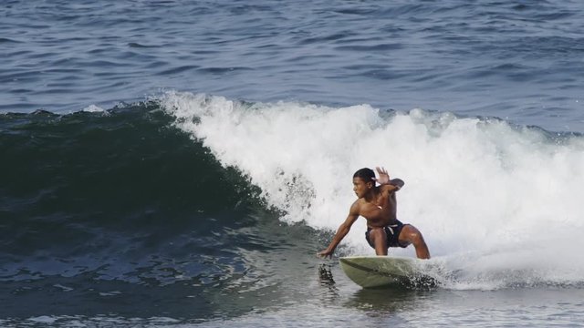Close up slow motion shot of Handsome guy surfing a green wave in Indonesia, Java