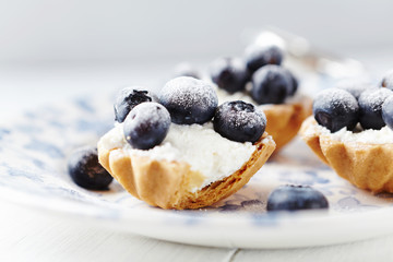 Little mascarpone tart with fresh bilberries on bright background. Close up. 