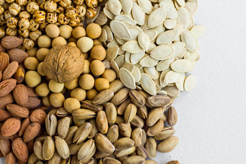 Designed a heap of  shelled nuts varieties on the white fabric surface.Top and half view
