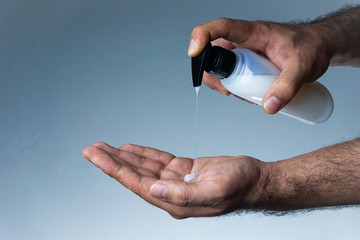 Men's hand that applying disinfectant to cleaning. Sanitizer for Coronavirus, Covid-19, SARS-CoV-2 outbreak. 2019 Novel Coronavirus concept. Blue soft background.