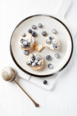 Little mascarpone tart with fresh bilberries on wooden background. Top view.