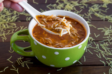 Hand holding a spoon of traditional Turkish vermicelli soup on soup bowl,close up taken